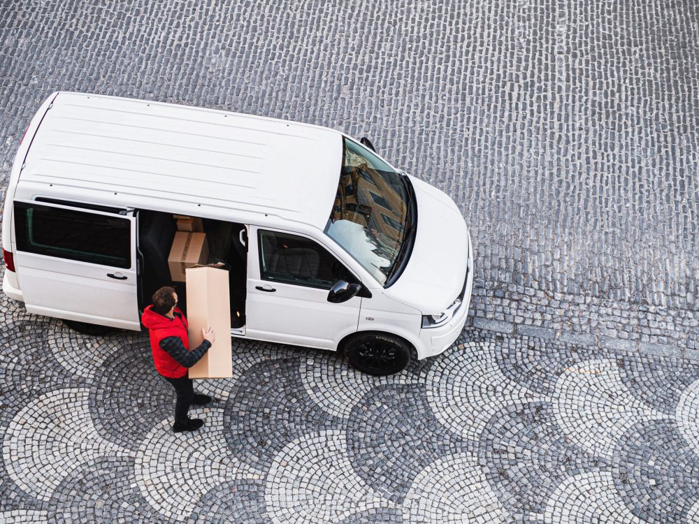 An aerial view of delivery man courier with face mask delivering parcel box in town.